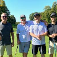 Four alums standing on the golf course.